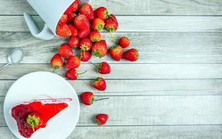 top visie van vers aardbei taart plakjes Aan een bord en vers rood aardbeien fruit Aan een blauw oud houten achtergrond foto