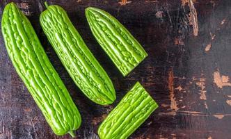 top visie van vers groen bitter meloen of bitter kalebas groente in een mand geplaatst Aan een oud houten achtergrond foto