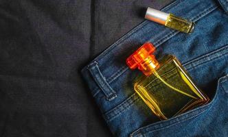 gouden parfum flessen en geuren in jeans zak- Aan zwart achtergrond foto