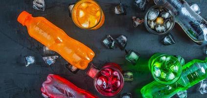 top visie veel van flessen zacht drankjes in kleurrijk en smaakvol Aan de tafel, bril met zoet drankjes met ijs kubussen foto