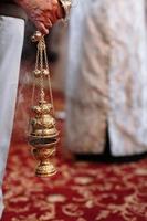 een priester in de orthodox christen kerk houdt in zijn handen de wierookvat foto