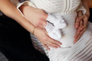 jong koppel verwacht baby knuffelen maag. zwangerschap en mensen concept foto