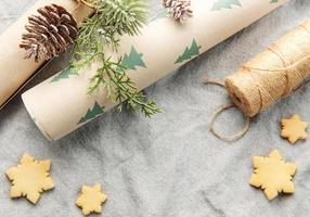 omhulsel papier met een pijnboom Afdeling en Kerstmis koekjes Aan een textiel achtergrond foto