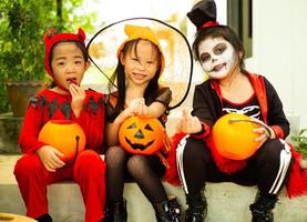 portret van gelukkige zussen in halloween-kostuum die voor de deur zitten en wachten op trick or treat. fijne halloweendagen foto