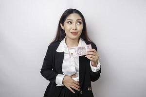 foto van een hongerig opgewonden jong zakenvrouw Holding geld in Indonesisch roepia en benieuwd wat naar bestellen lekker voedsel geïsoleerd Aan wit kleur achtergrond