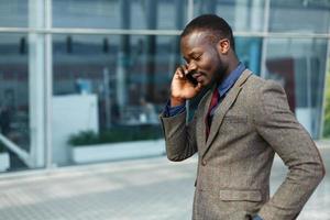 stijlvolle Afro-Amerikaanse zwarte zakenman gesprekken op zijn smartphone foto