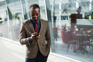 stijlvolle Afro-Amerikaanse zwarte zakenman werkt op zijn smartphone