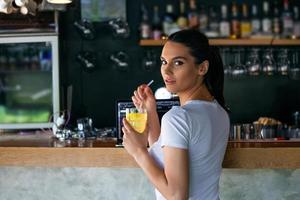 portret van mooi jong vrouw genieten van een drankje, mooi meisje nippen citroen sap in koffie winkel terras foto