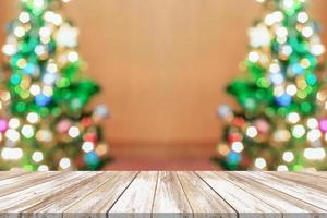 leeg hout tafel top met vervagen Kerstmis boom met bokeh licht achtergrond foto