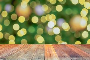 leeg hout tafel top met vervagen Kerstmis boom met bokeh licht achtergrond foto