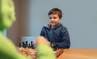 geconcentreerd jong jongen ontwikkelen schaak strategie, spelen bord spel met vriend of familie Bij huis. werkzaamheid of hobby voor familie concept foto