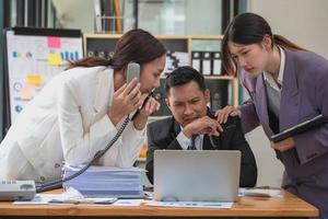 een team van bedrijf mensen zijn bezig werken Aan de telefoon. laptop computer en document grafieken in werken binnen de kantoor foto