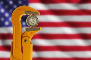 drie Cubaans peso munt gehouden in een oranje loodgieter moersleutel tegen de achtergrond van de Verenigde Staten van Amerika vlag foto