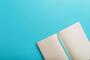 Open notitieboekje, een boek met blanco en blanco Pagina's Aan een blauw achtergrond, top visie. foto