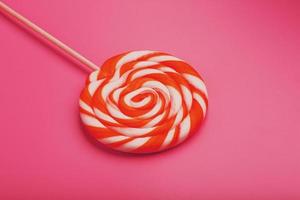 oranje lolly Aan een roze achtergrond met een zacht contrast. minimaal concept met kopiëren ruimte. foto