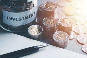 geld besparing en investering ideeën en winst groei, investering planning en strategie, financieel beheer en bedrijf strategie.voor succes, munt, glas kan, pen allemaal Aan de tafel foto