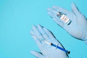 dokter handen in medisch handschoenen Holding een flacon van vaccin en spuit, top visie. globaal bevolking vaccinatie concept foto
