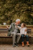 opa uitgeven tijd met zijn kleindochter Aan bank in park Aan herfst dag foto