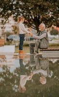 opa uitgeven tijd met zijn kleindochter door klein water zwembad in park Aan herfst dag foto