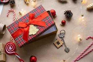 sleutel naar huis met sleutelhanger Aan knus huis in geschenk doos met Kerstmis decor verpakking. pak Cadeau voor nieuw jaar, kerstmis. gebouw, projecteren, in beweging naar nieuw huis, hypotheek, huur, aankoop echt landgoed foto