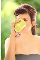 mooi meisje het drinken van thee of koffie binnen. groene onscherpe achtergrond foto