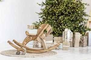 knus nieuw jaar interieur van de kamer, een kinderen paard en een Kerstmis boom zijn versierd met slingers, geschenken, speelgoed, kaarsen, lantaarns. feestelijk leven kamer. nieuw jaar. foto