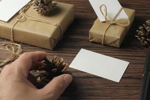 mannetje handen omhulsel nieuw jaar cadeaus en schrijven kaarten Aan een bruin houten tafel. foto