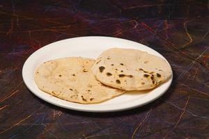 Indisch traditioneel keuken chapati of roti, of Indisch brood in wit bord met meel foto