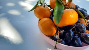 dichtbij omhoog, roze bord met citrus fruit en druiven Aan wit achtergrond. gezond fruit 02 foto