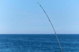 visvangst hengel tegen blauw oceaan of zee achtergrond, kopiëren ruimte. aan het wachten voor grootste lading. meditatief kom tot rust sport. foto