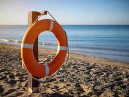 helder oranje reddingsboei Aan een zanderig strand Aan een zonnig zomer dag. foto