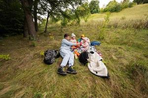 picknick in herfst park. vader met drie kinderen eten in de Woud. foto