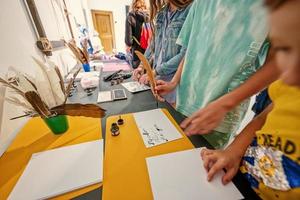 kinderen schrijven met veer schacht pen Bij bureau. foto