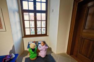 twee zussen zitten Bij de tafel tegenover venster en tekenen. foto