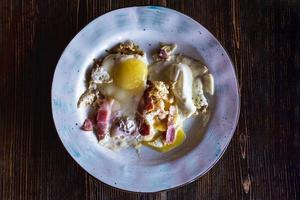 gebakken eieren en spek Aan een bord Aan een ruw houten tafel, ontbijt in een restaurant, top visie foto