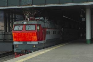 een passagier trein is staand Bij de station platform aan het wachten voor vertrek, st. petersburg, ladozjski spoorweg station foto