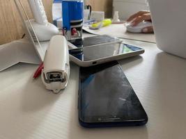 twee werken touch screen mobiel telefoons, smartphones liggen Aan de tafel in de kantoor met briefpapier, een nietmachine, een zegel en een laptop foto