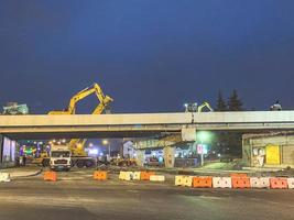 bouw van een brug in de stad centrum. de weg is omheind met beschermend elementen van auto's. de viaduct gebarsten en het is wezen gerepareerd Bij nacht foto