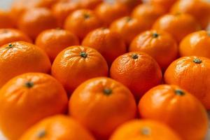 mand met mandarijn of oranje fruit Aan een grijs plaid achtergrond. foto