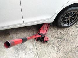 wit auto's verandering wielen gebruik makend van een hijs- krik. foto