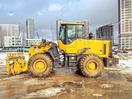 bouw uitrusting Aan plaats. gebouw huizen en houdende wegen. helder, geel graafmachine voor graven gaten en houdende loodgieter communicatie foto