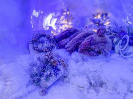 feestelijk ontwerp tafereel een speelgoed- beer slaapt in een met sneeuw bedekt hol, een versierd boom achter hem foto