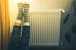 poten met kleurrijk gebreid winter Kerstmis sokken Aan voeten opwarming Aan centraal verwarming radiator verwarming. winter tijd, verkoudheid weer seizoen vieringen eenzaamheid Bij huis alleen foto