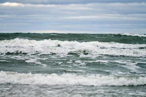 blauwe zee met schuimende golven en bewolkte lucht, zeegezicht foto