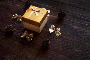 Kerstmis Cadeau Aan rustiek houten achtergrond. winter achtergrond met bogen, kegels enz in gouden kleur. foto