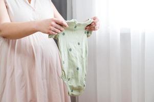zwanger vrouw voorbereidingen treffen kleren voor haar baby. foto