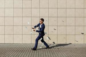 jonge zakenman gooit dollars rond en danst op straat foto