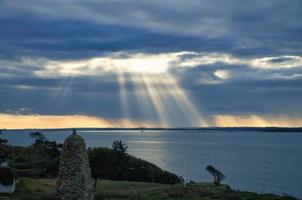 Aan de kust van gejaagd. zon stralen breken door de dramatisch lucht door de wolken foto