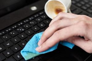 hand- reinigt gemorst koffie Aan laptop toetsenbord met een vod foto