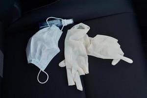 beschermend masker medisch handschoenen en antibacteriële ontsmettingsmiddel Aan de auto stoel foto